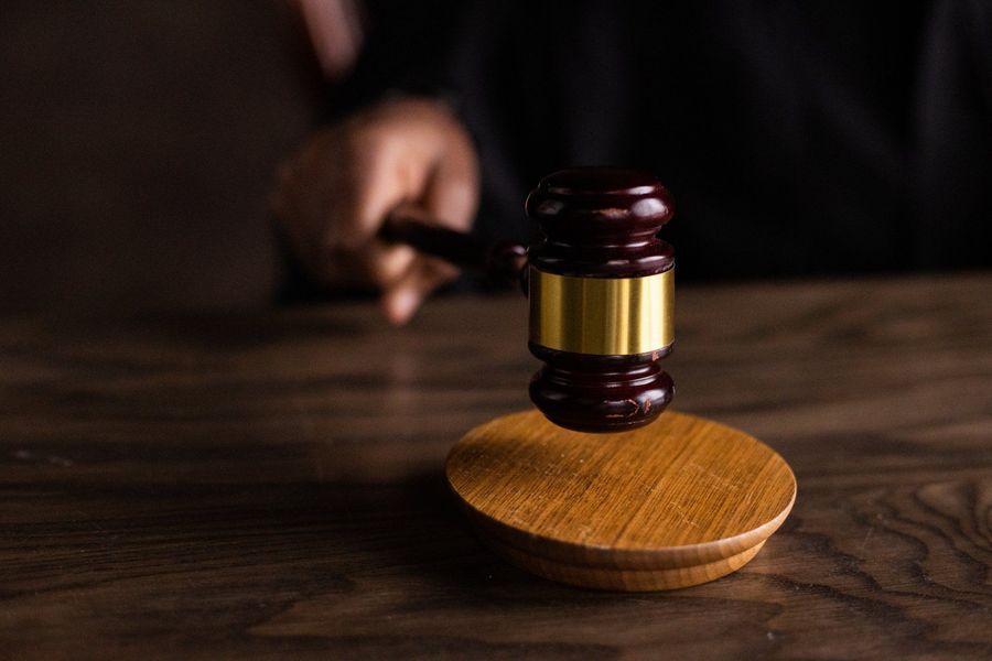 A judge holding a wooden gavel on a wooden table